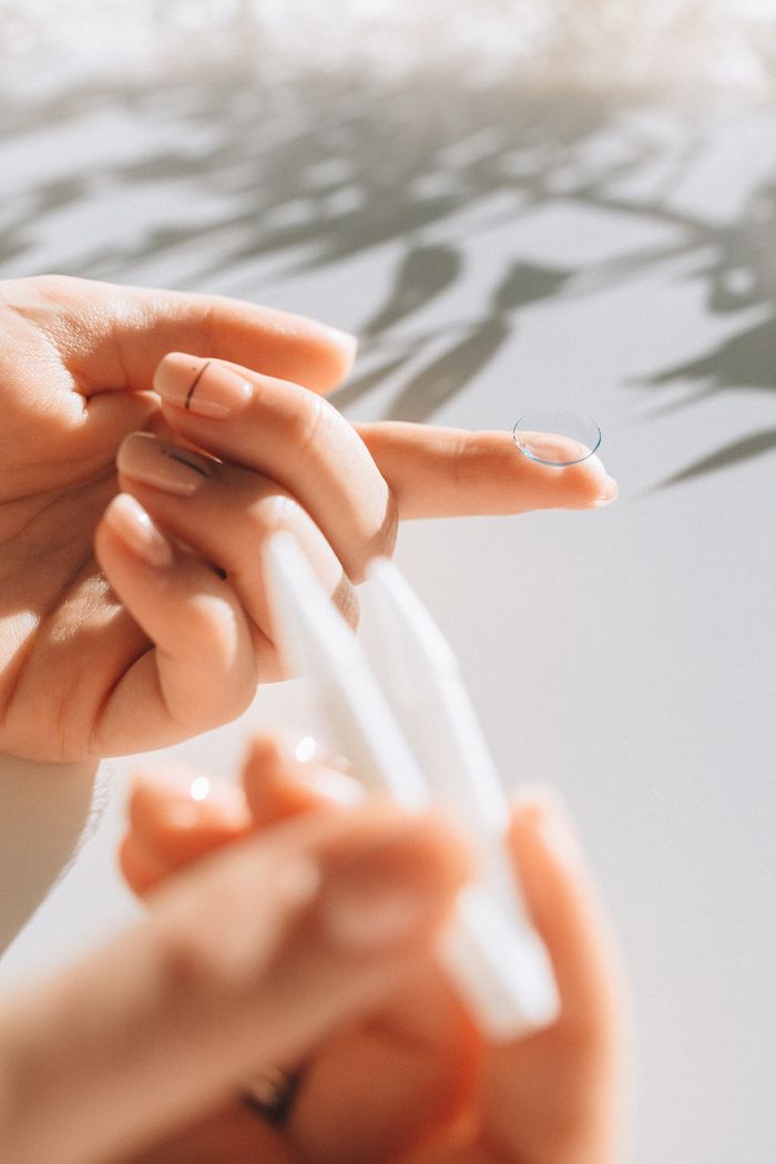 Detail shot of a contact lens on finger with natural light creating shadows, perfect for eyewear symbolism.