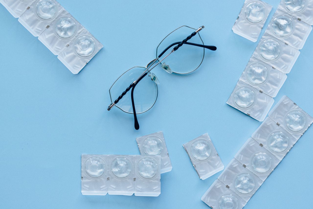 Eyeglasses and contact lenses on a blue background. Concept of eye care and vision correction.
